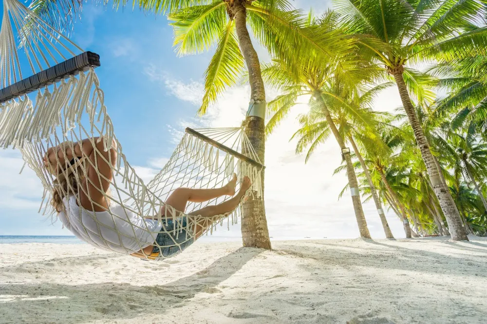 Person relaxing in hammock on beach